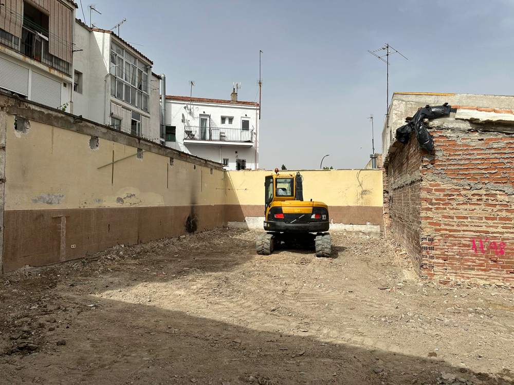 Solar en Carabanchel tras el derribo de la casa, con la excavadora al fondo