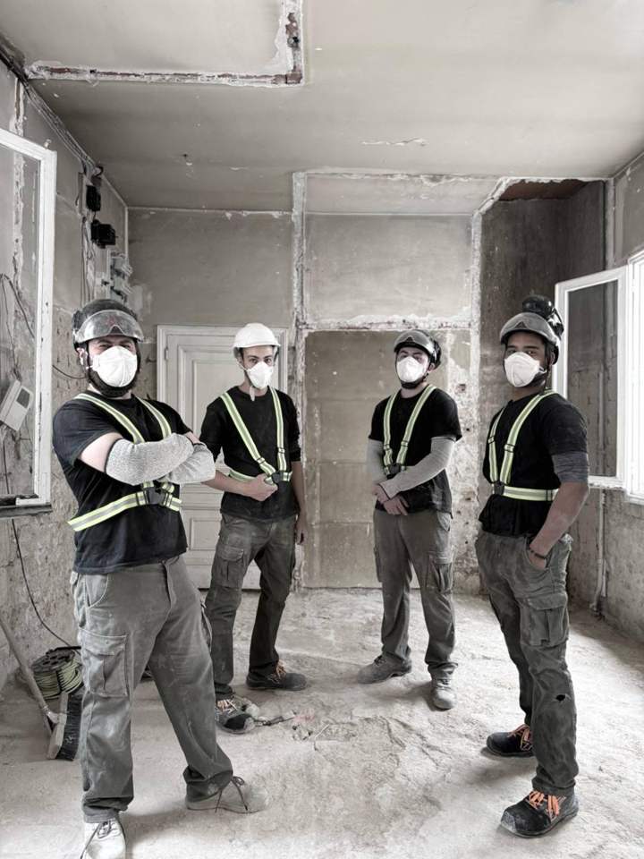 Operarios de AZAMA Demoliciones con casco, mascarilla FFP y arnés reflectante en una obra de Madrid